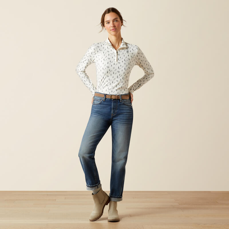 Woman wears Ariat Lowell 3.0 Forest Horses Print baselayer, blue jeans, against plain background.