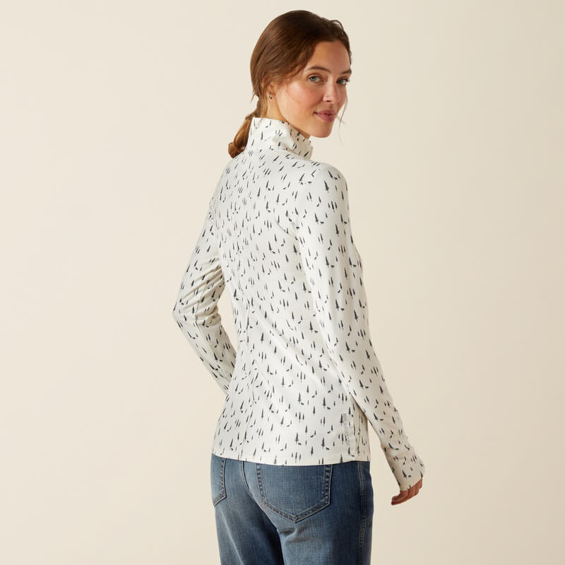 Woman in Ariat Lowell 3.0 Forest Horses baselayer, smiling over her shoulder in jeans.