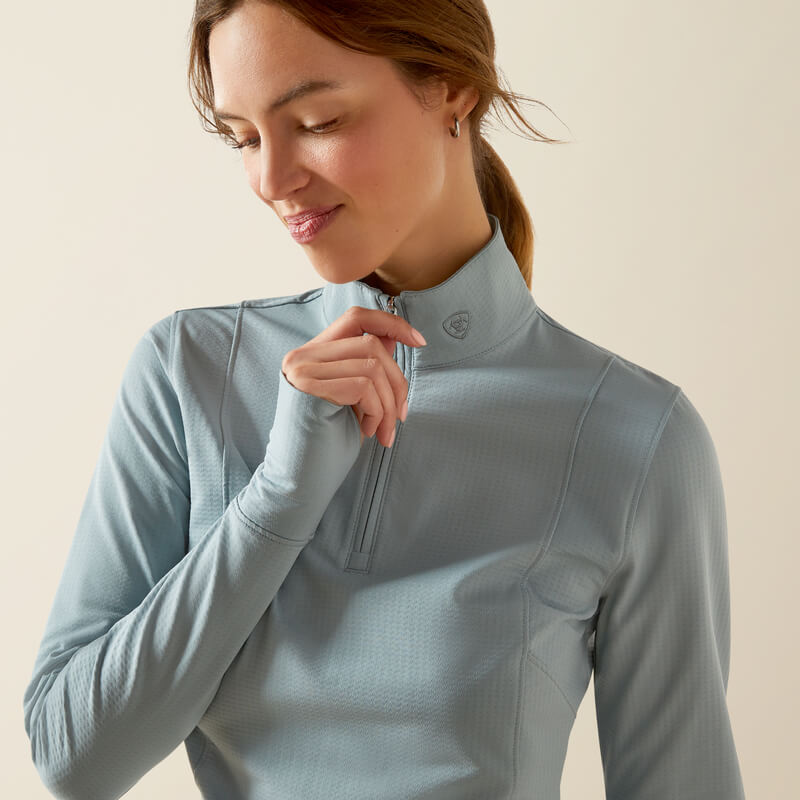 Woman in Ariat Womens Gridwork 2.0 1/4 Zip Baselayer Lead and jeans, smiling against a plain background.