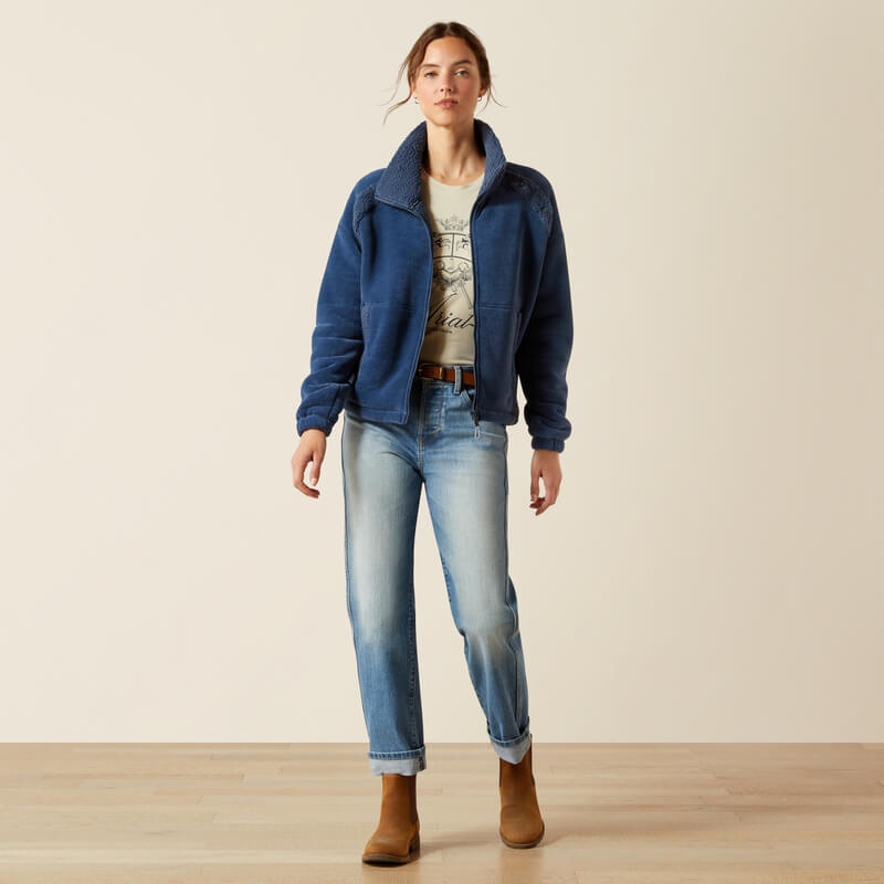 Woman in blue jeans wears Ariat Lafayette Full Zip Fleece Big Dipper indoors on wooden floor.