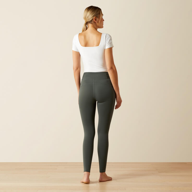 Woman in white top and Ariat Womens Avail 2.0 Half Grip Tight Urban Chic stands barefoot indoors.