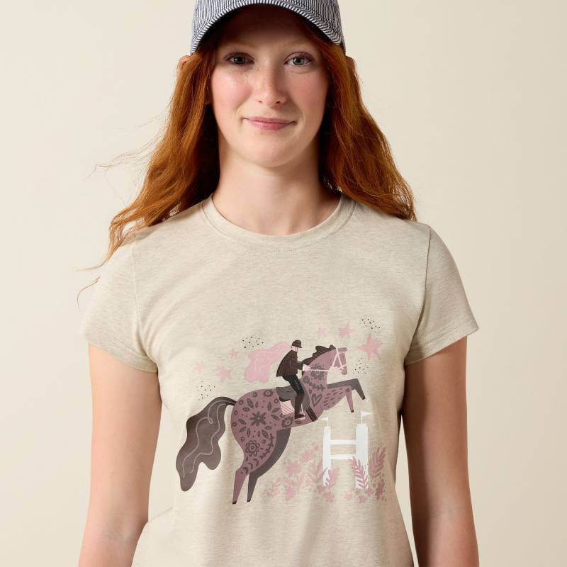 Woman in cap and jeans wearing Ariat Youth Floral Leap SS T-Shirt Oatmeal.