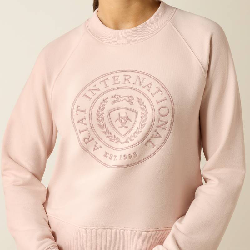 Woman in Ariat Womens Martine Sweatshirt Sepia Rose and brown cap stands with arms relaxed.