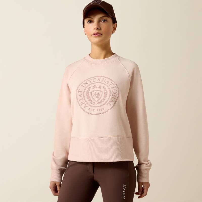 Woman in Ariat Womens Martine Sweatshirt Sepia Rose and brown cap stands with arms relaxed.