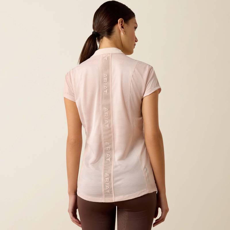 Woman facing away in a sepia rose Ariat Breathe cap sleeve baselayer with ARIAT text.