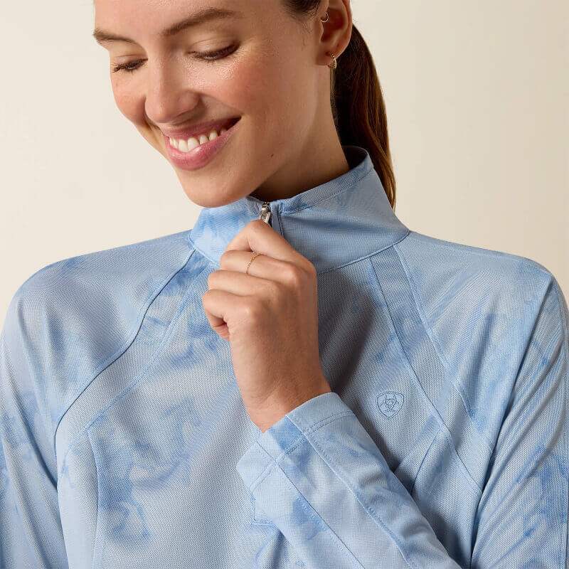 Woman in Ariat Sunstopper 3.0 Baselayer St. Tropez Mirage Print and jeans against plain backdrop.