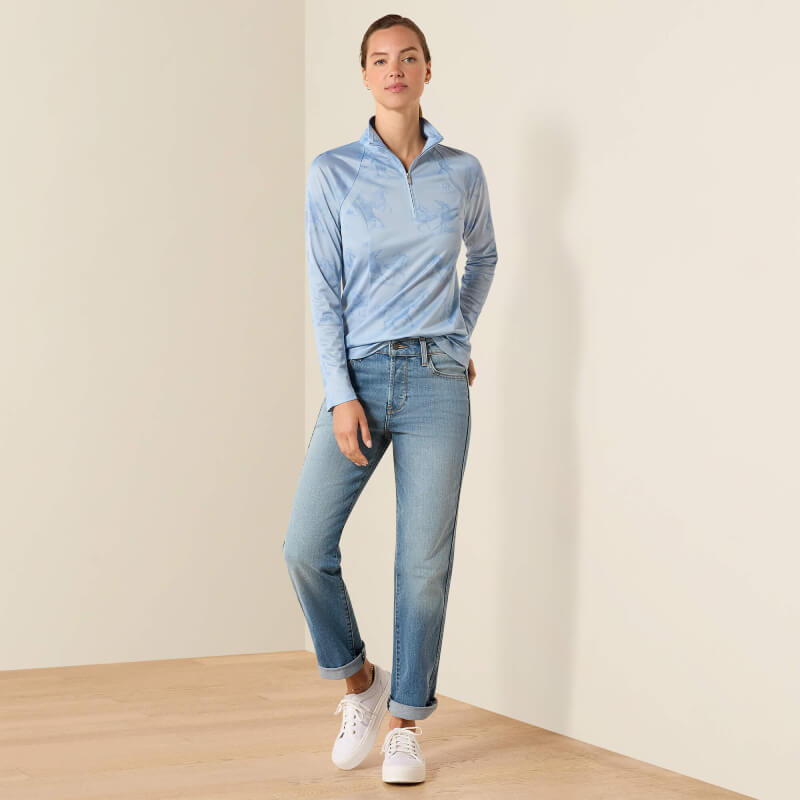 Woman in Ariat Sunstopper 3.0 St. Tropez Mirage Print Baselayer and jeans, in a simple room.