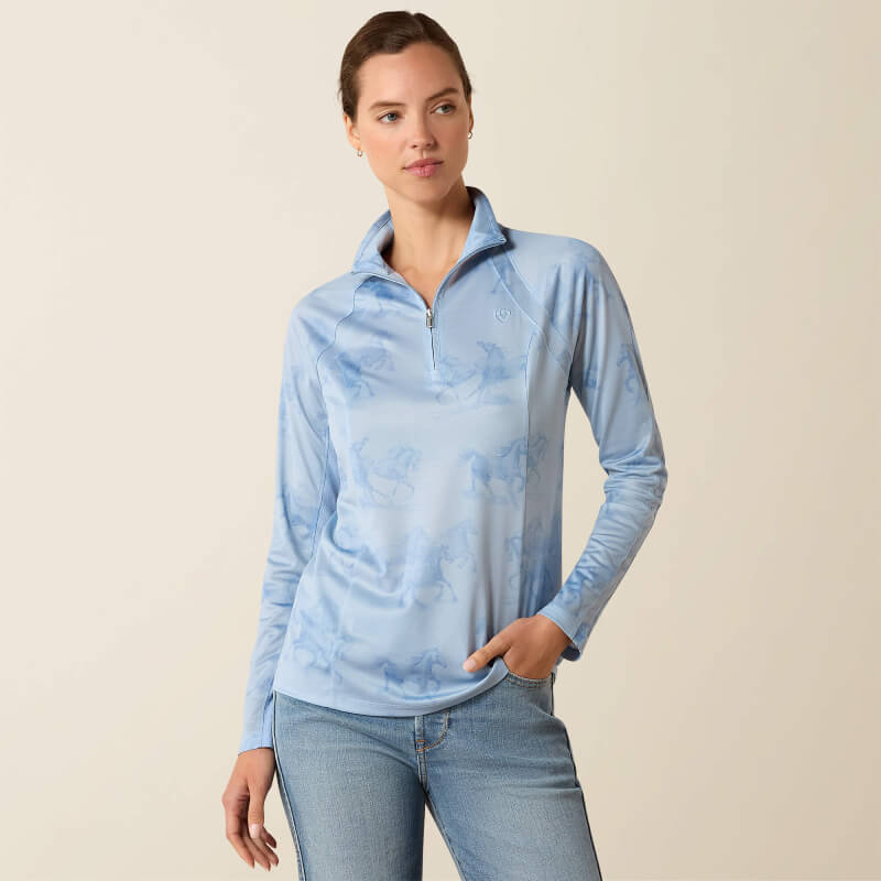 Woman in Ariat Sunstopper 3.0 Baselayer St. Tropez Mirage Print and jeans against plain backdrop.