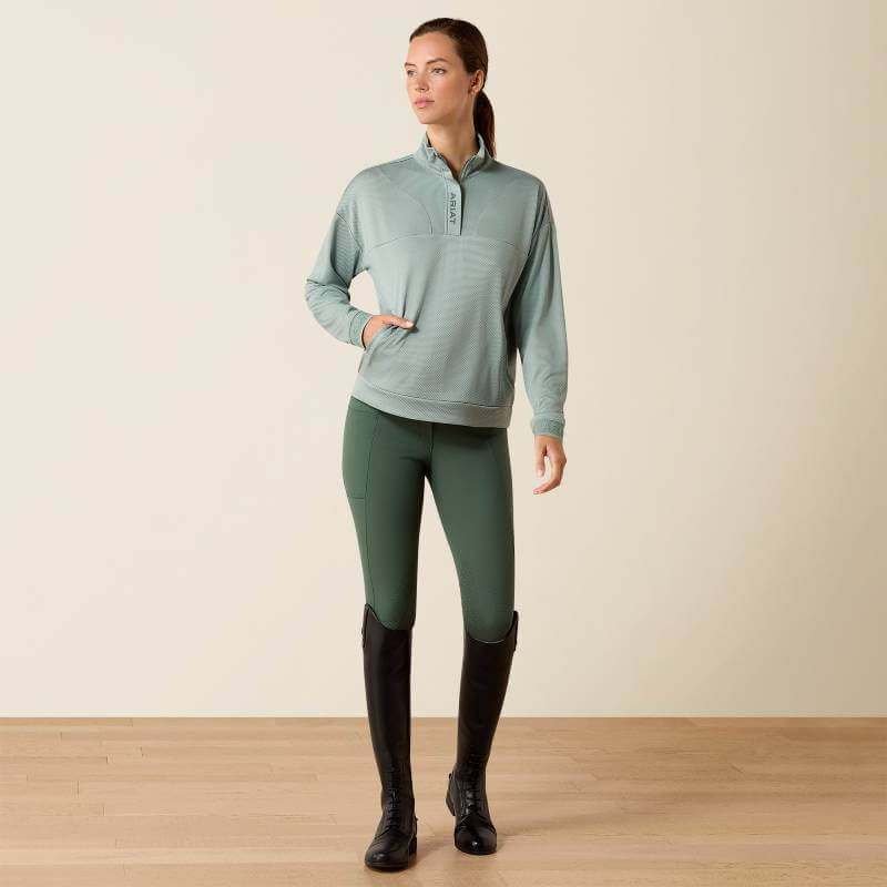 Woman in Ariat Breathe 1/2 Zip Pullover (Chinois Green), green leggings, black riding boots.