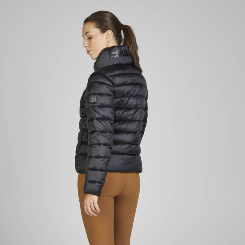 Woman in Eskadron Heritage Quilt Jacket Black and brown leggings, standing sideways, gray background.