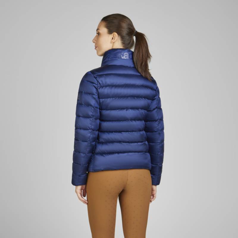 Woman wears Eskadron Heritage Quilt Jacket True Blue and brown pants, back to camera.