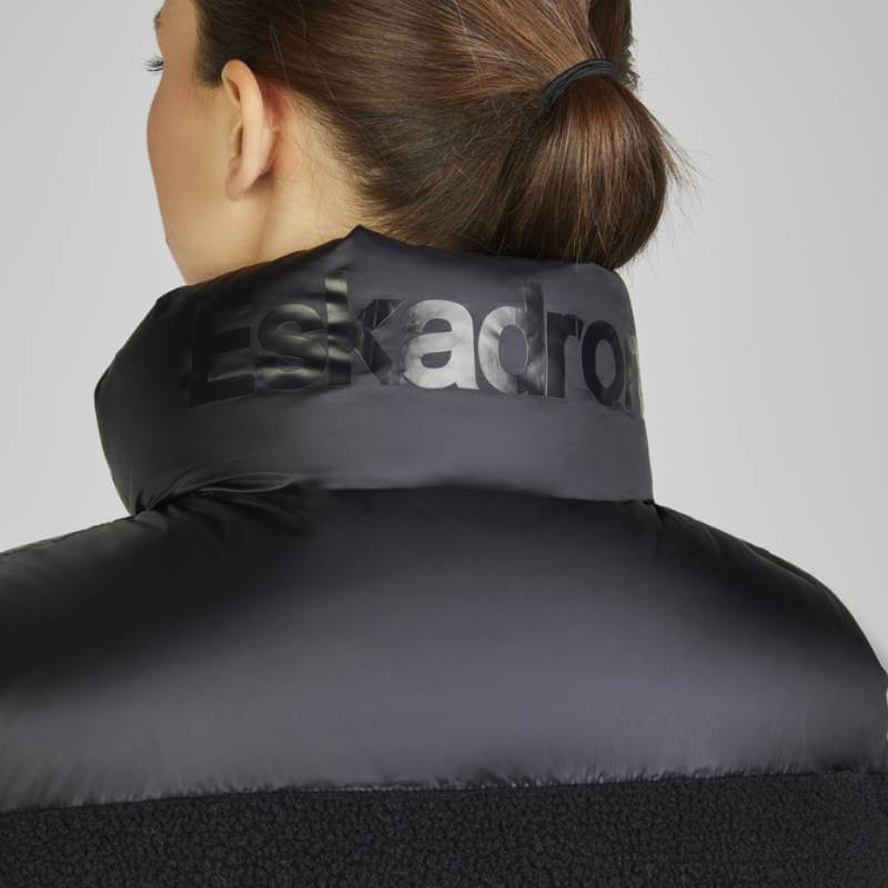 Woman with brown hair in a bun, seen from behind in Eskadron Heritage Quilt Waistcoat Teddy Black.