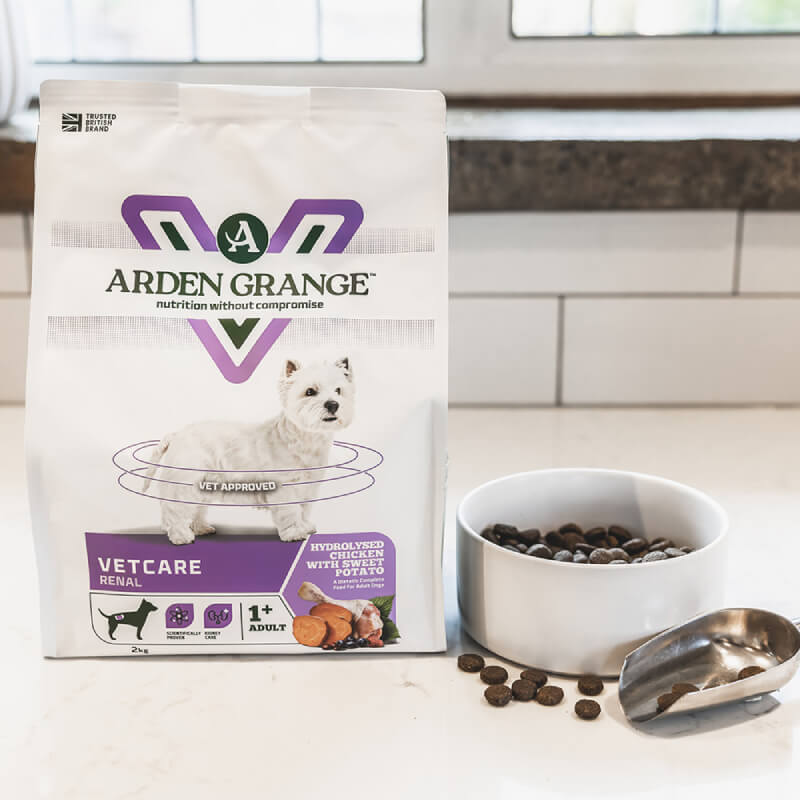 Arden Grange VetCare Renal dog food bag next to a white bowl of kibble on the countertop.