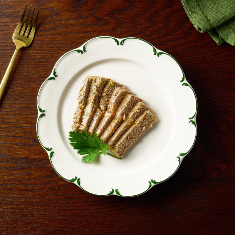 A slice of pâté with garnish and a fork, next to Canagan Petite Country Game Pate for Dogs 100g.