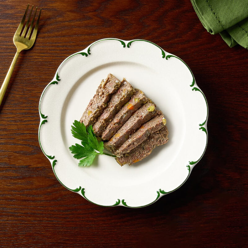 Six slices of meatloaf with parsley on a plate, featuring Canagan Petite Beef Stew Pate for Dogs.