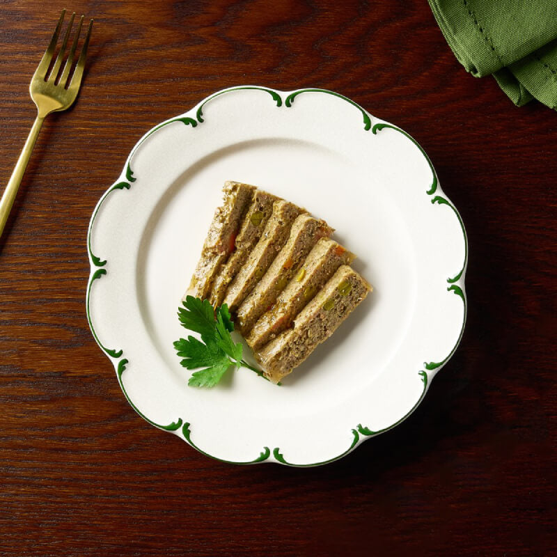 Slice of Canagan Petite Turkey & Duck Pate for Dogs, parsley garnish, on a white trimmed plate.