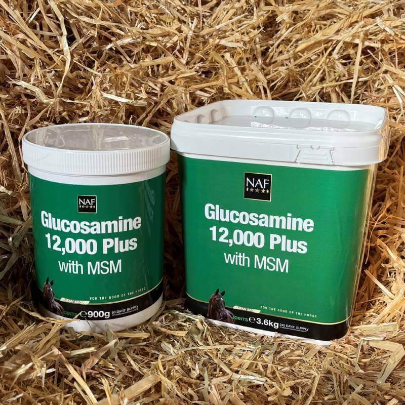 Two green tubs of NAF Glucosamine 12000 Plus MSM for horses on a bed of straw.