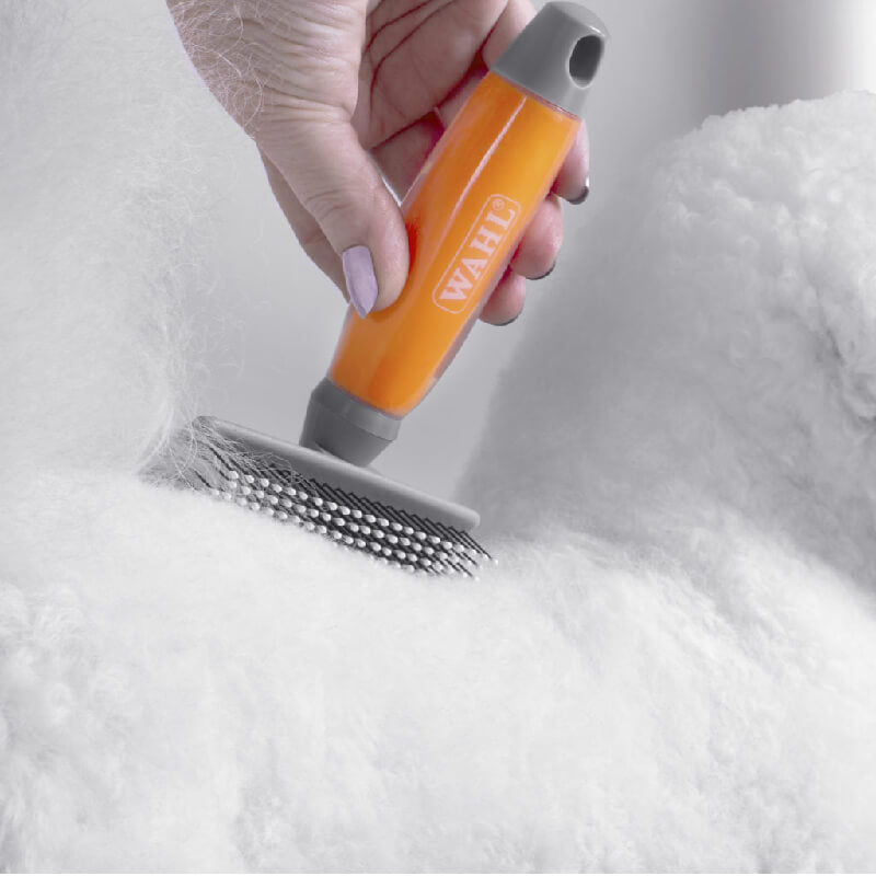 Brushing a fluffy white dog with the Wahl Large Nylon Slicker Brush Orange Gel Handle.