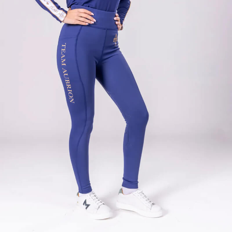 Person wearing Aubrion Team Winter Riding Tights Navy with full seat grips and white sneakers.