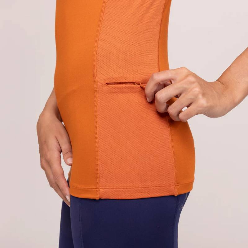 Person in Aubrion Team Sleeveless Baselayer Rust unzips a small side pocket on their shirt.