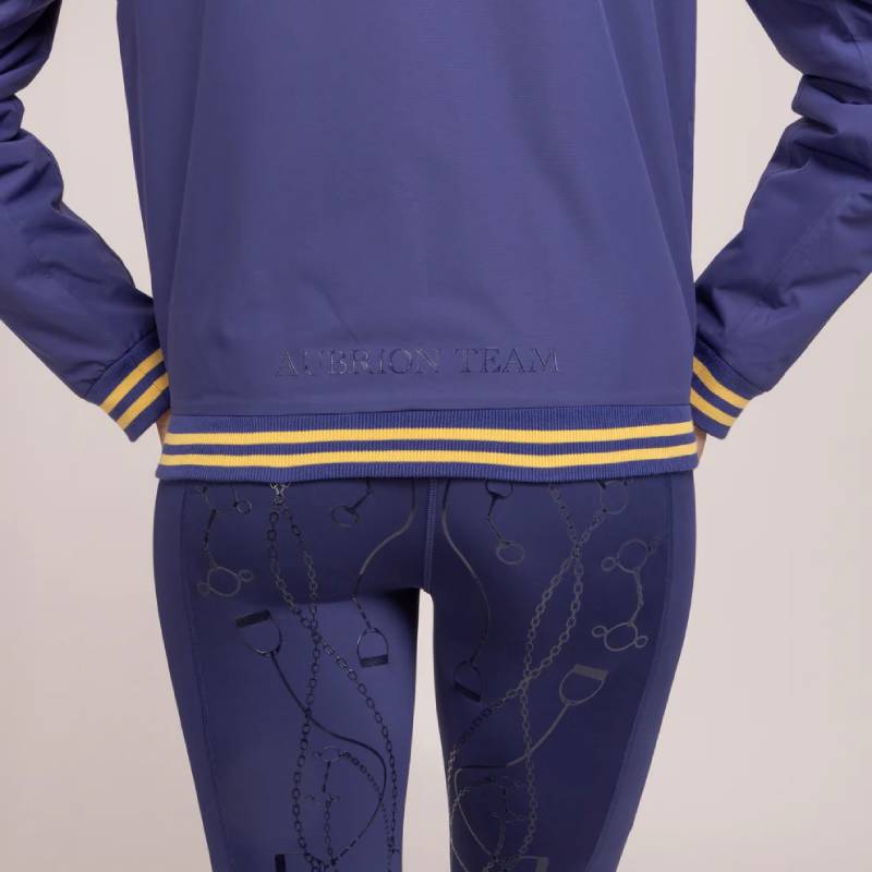 Person in an Aubrion Team Blouson Midnight jacket with yellow stripes and blue leggings, back view.