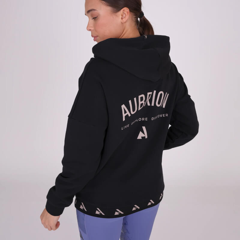 Woman in a black Aubrion React Hoodie Shadow and light purple leggings, facing away.