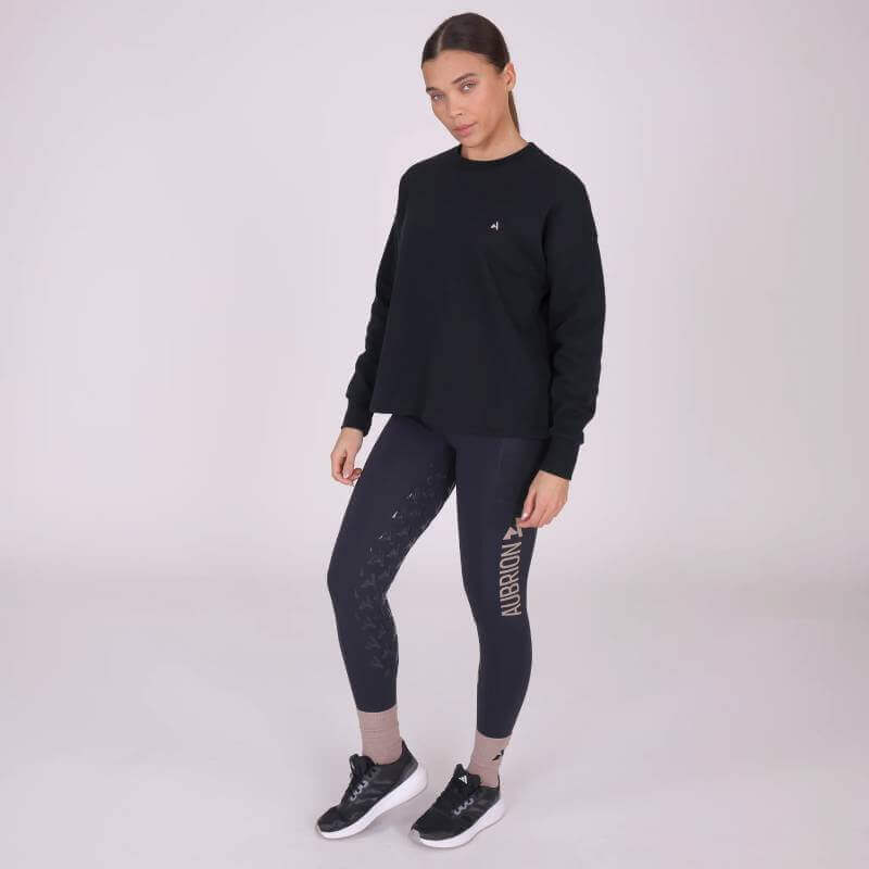 Woman in Shires Aubrion React Sweatshirt Shadow and leggings, standing against a plain background.