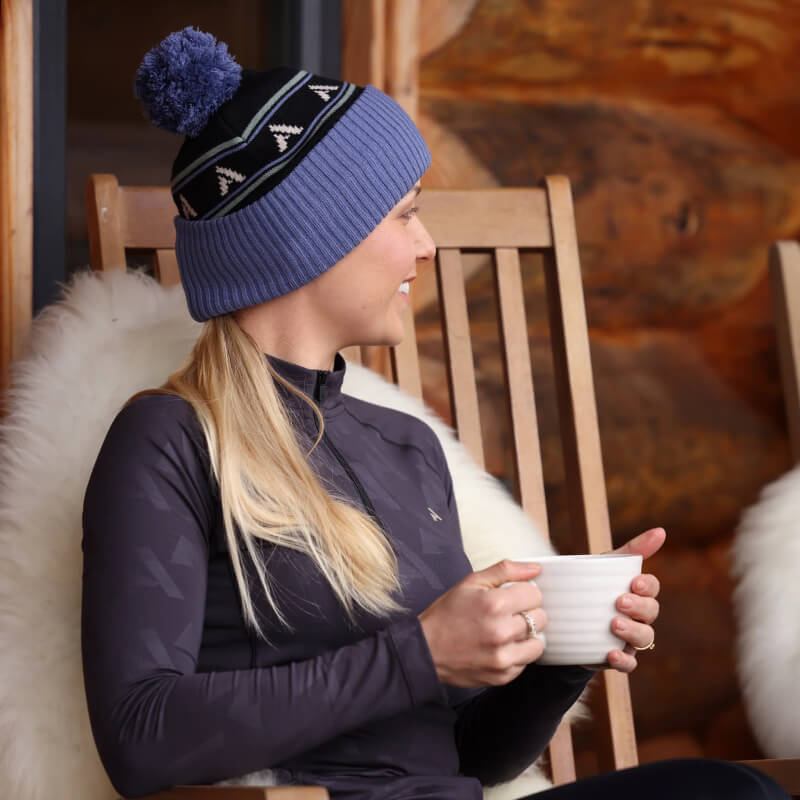 Woman in a blue knit hat enjoys warmth from her Aubrion React Winter Baselayer Shadow.