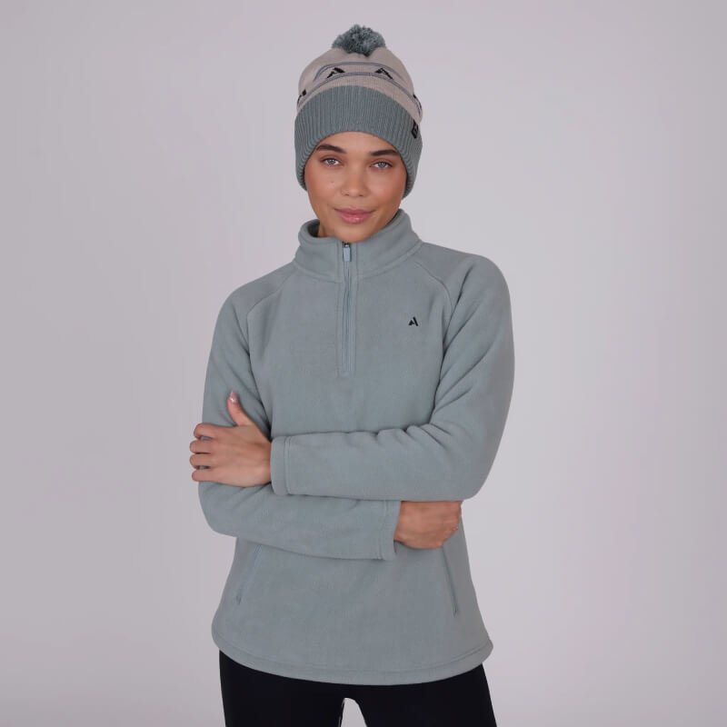 Woman wears Aubrion React Half Zip Fleece Sage with arms crossed against plain background.