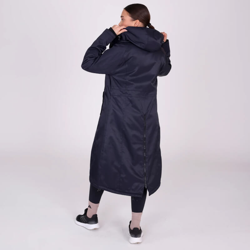 Woman wearing Shires Aubrion React Long Coat Shadow with leggings and sneakers on plain background.