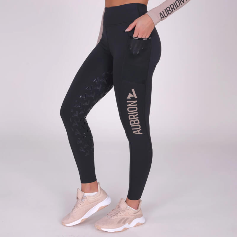 Woman wears Aubrion Non-Stop Riding Tights Shadow, posing against a plain background.