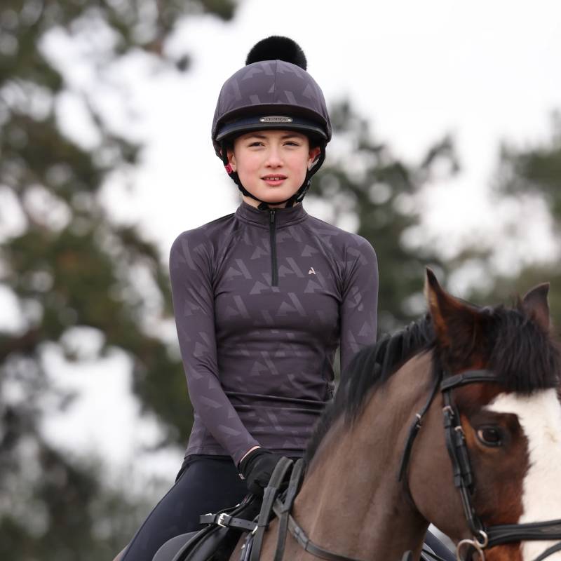 A young rider in a helmet wears the Aubrion React Winter Baselayer YR Shadow while riding outside.