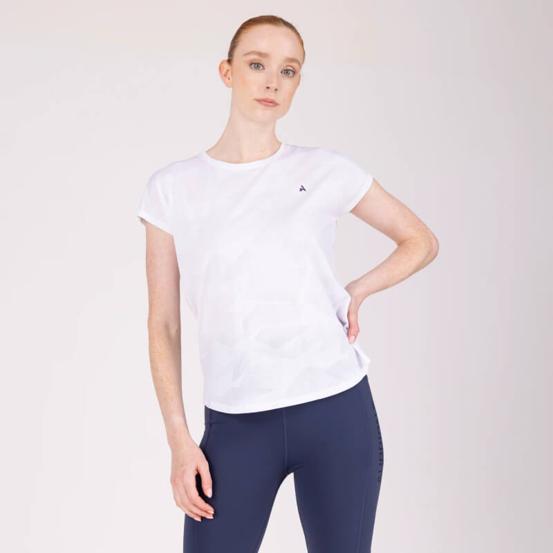 Woman in Aubrion React Tech T-Shirt White poses with one hand on her hip, wearing navy leggings.