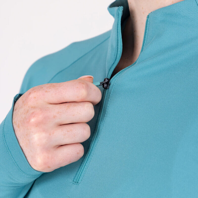 Woman in teal Aubrion React Long Sleeve Baselayer Haze poses against a white background.