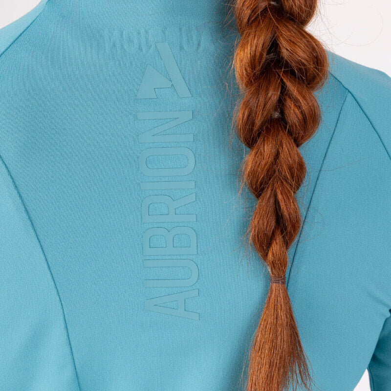 Person with a long red braid in a blue Aubrion React Long Sleeve Baselayer Haze, back view.