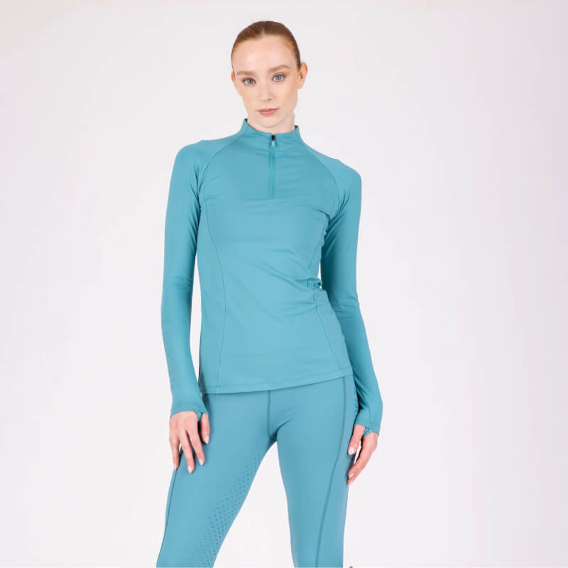 Woman in teal Aubrion React Long Sleeve Baselayer Haze poses against a white background.