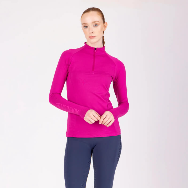 Woman in Aubrion React Long Sleeve Baselayer Fuchsia and navy leggings stands with arms crossed.
