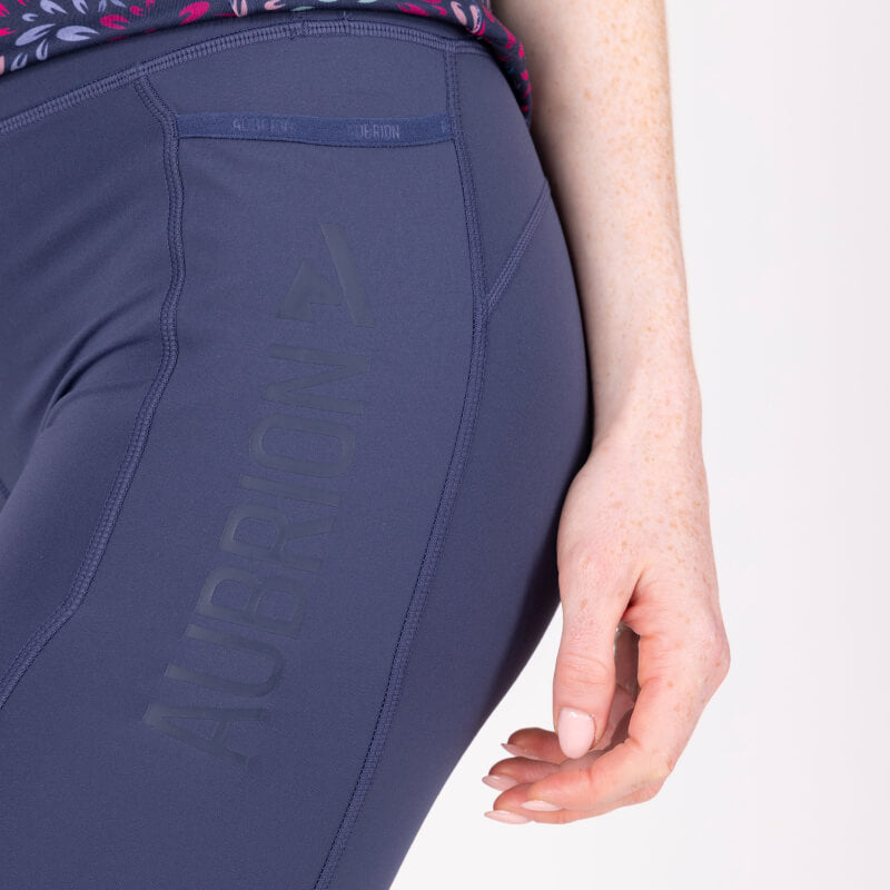 Woman in blue printed top and Aubrion React Non-Stop Shorts Midnight stands on white background.