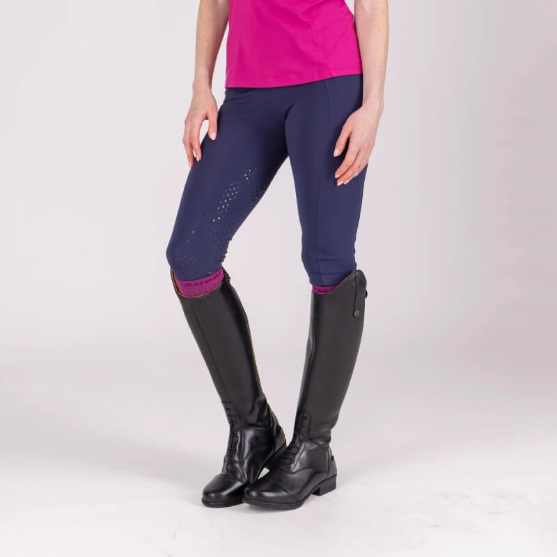 Person in black boots, Aubrion React Sculpt Riding Tights Midnight, and pink shirt stands.