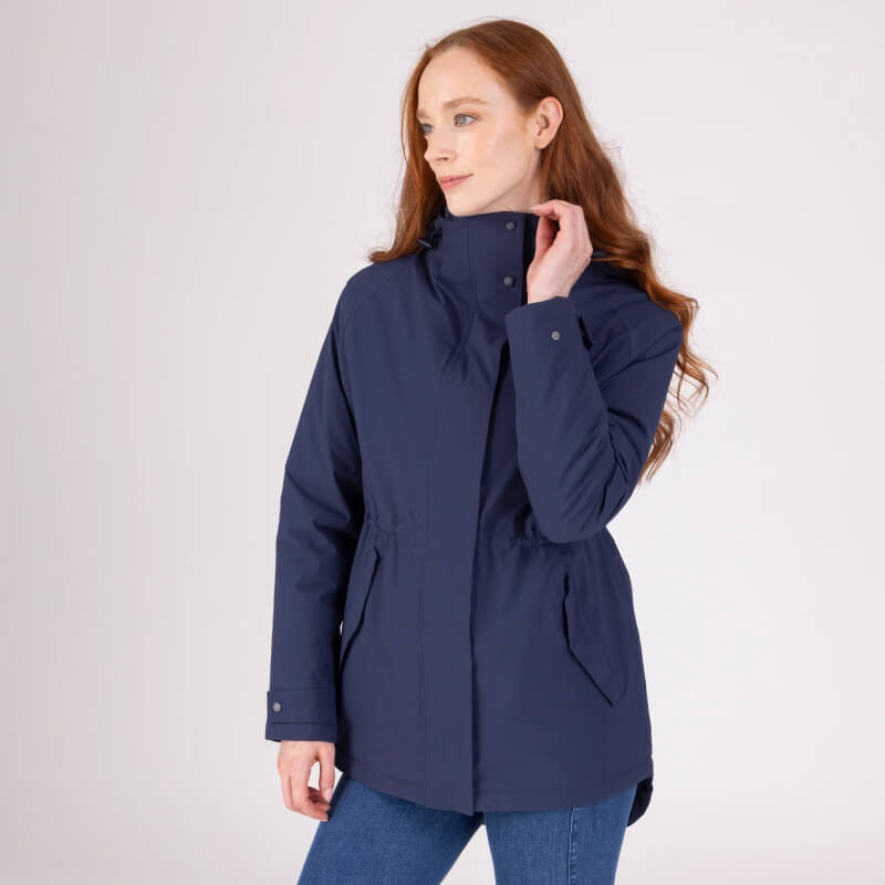 Woman with long red hair wears Aubrion Equestrian Lightweight Coat Midnight against plain backdrop.