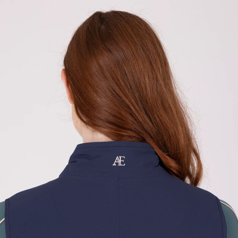 Woman with long brown hair wears Aubrion Equestrian Gilet Midnight, seen from behind.