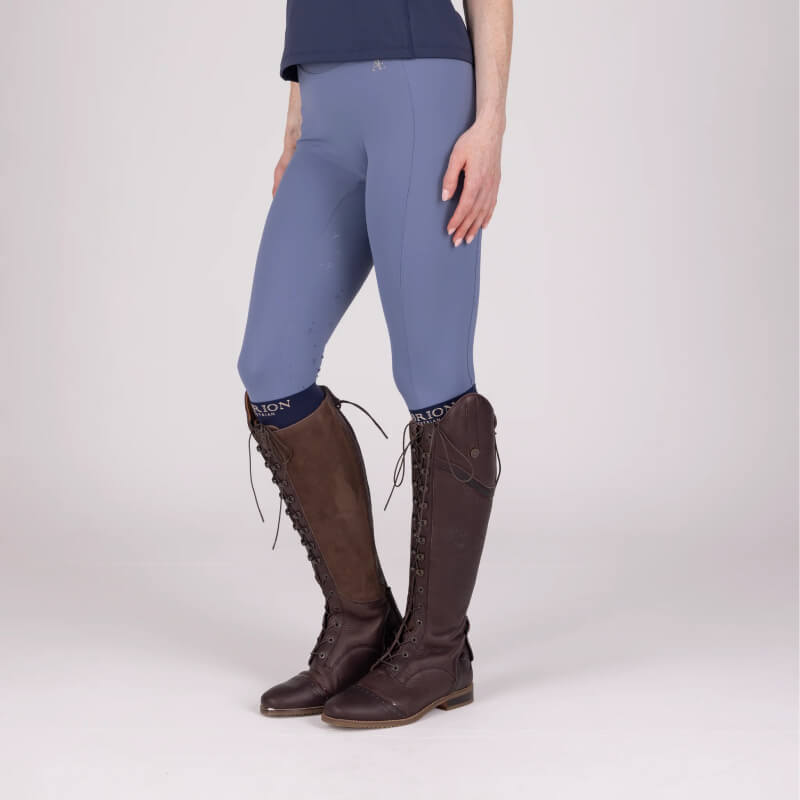 Person wearing Aubrion Equestrian Riding Tights Storm with long brown boots and navy socks.