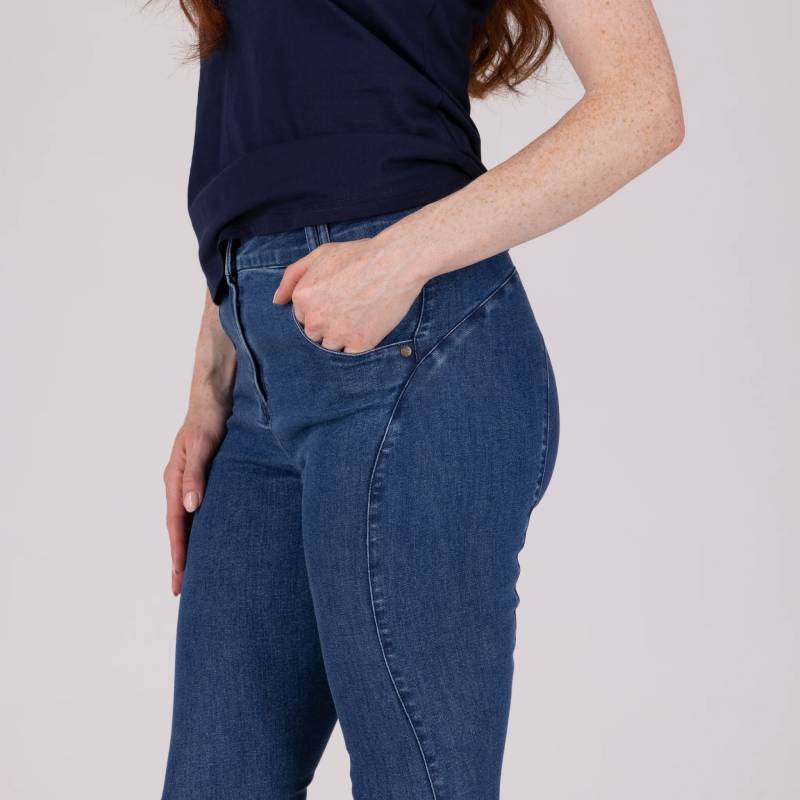 Person in Aubrion Equestrian Jeans Denim & navy shirt, hand in pocket, shoulders to thighs.