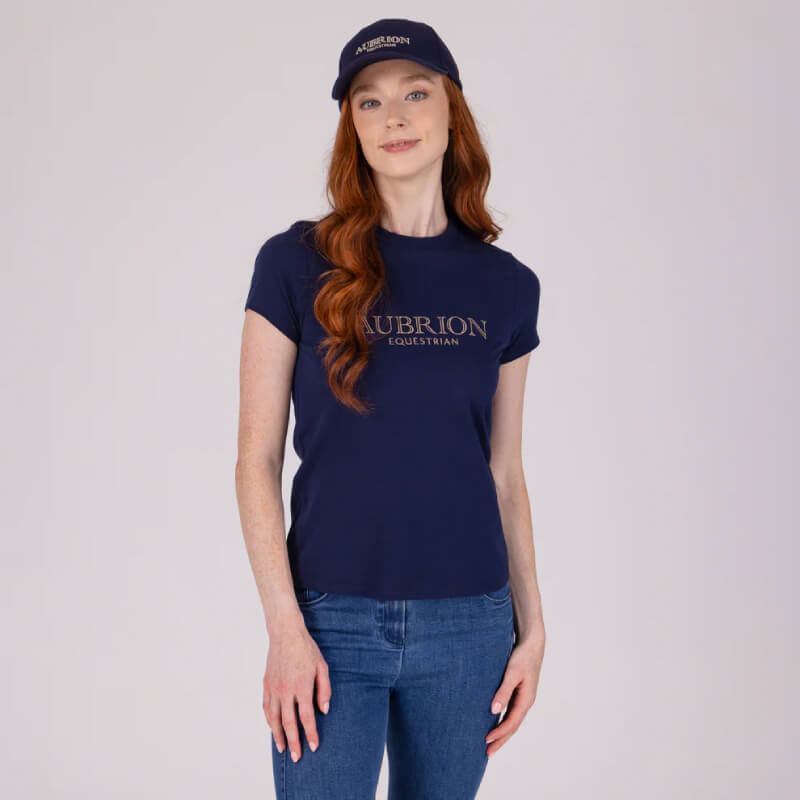 Woman in Aubrion Midnight T-Shirt and cap, standing against a plain background.