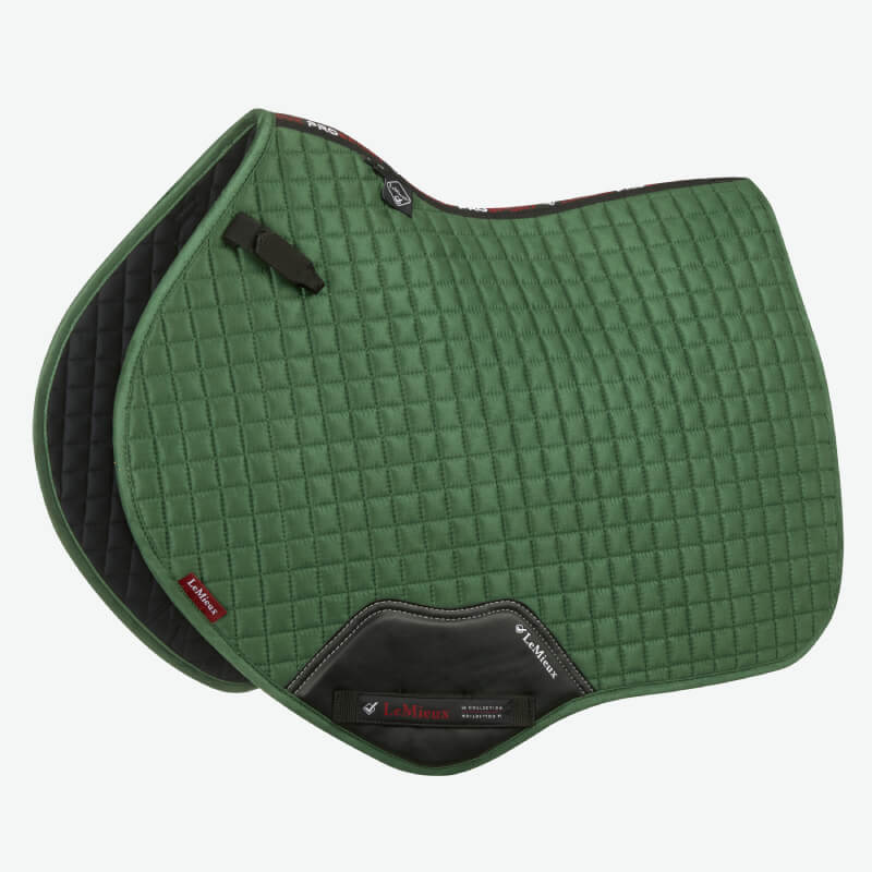 A person rides a brown horse through water with a LeMieux Suede Close Contact Square Hunter Green.