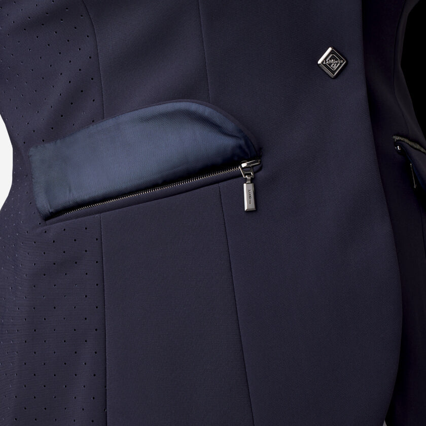 Close-up of the LeMieux Dynamique Show Jacket Ladies Navy, with zippered pocket and lapel pin.
