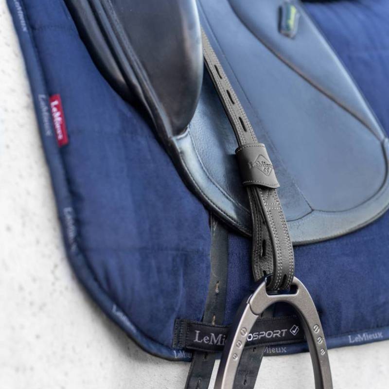 Close-up of a blue LeMieux saddle pad and black LeMieux Vector Close Contact Stirrup Leather.