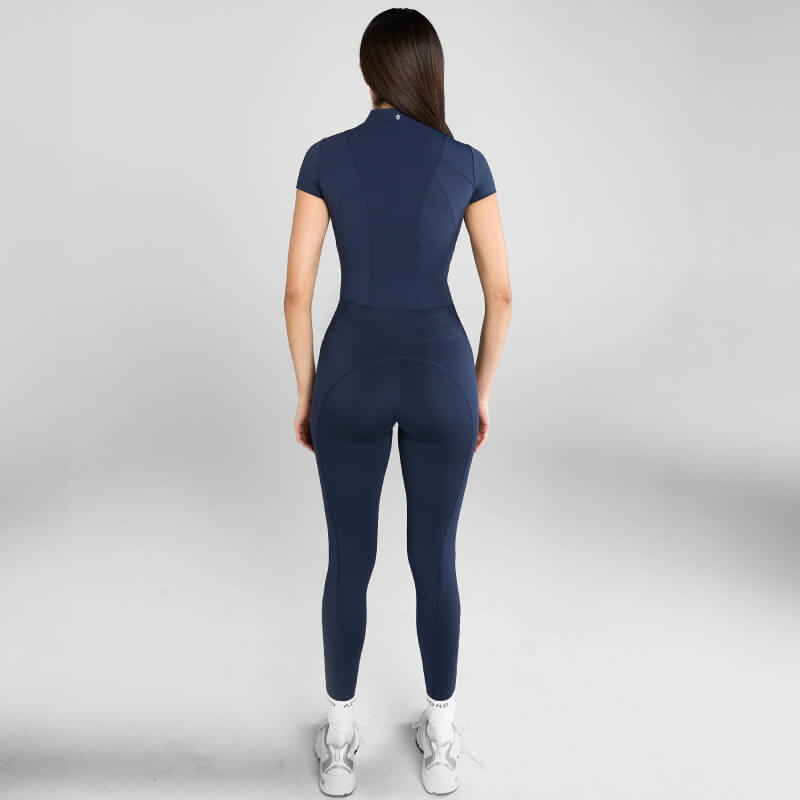 Woman in Aztec Diamond Core Navy Baselayer, white sneakers, back facing the camera.