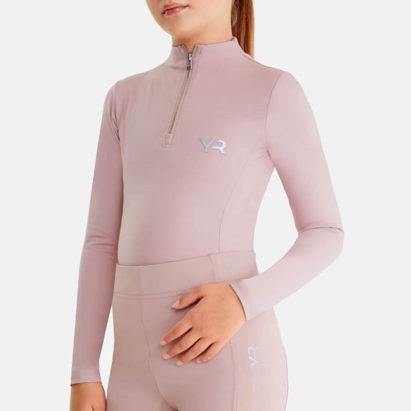 Girl in Aztec Diamond YR Baselayer Pink stands smiling, one hand on her hip.