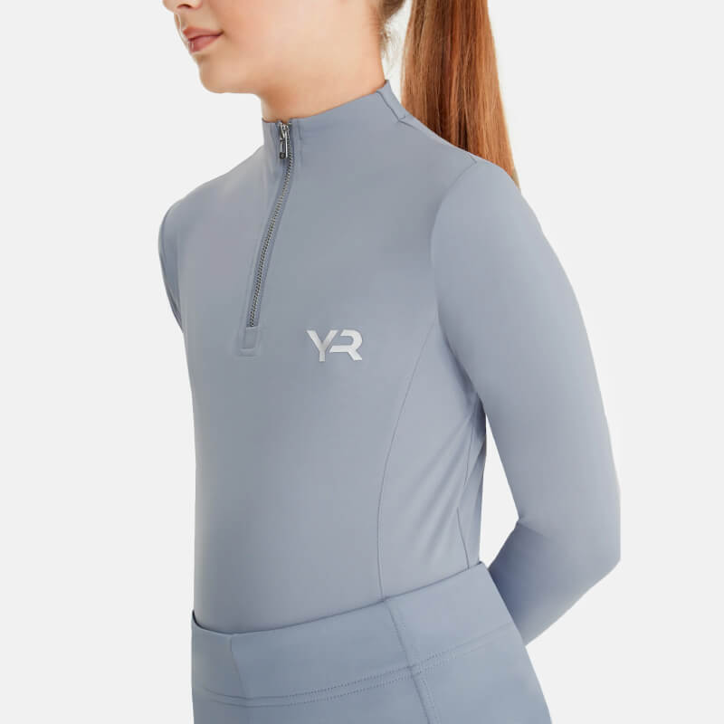 Young girl in an Aztec Diamond YR Baselayer Ash Blue, standing against a white background.